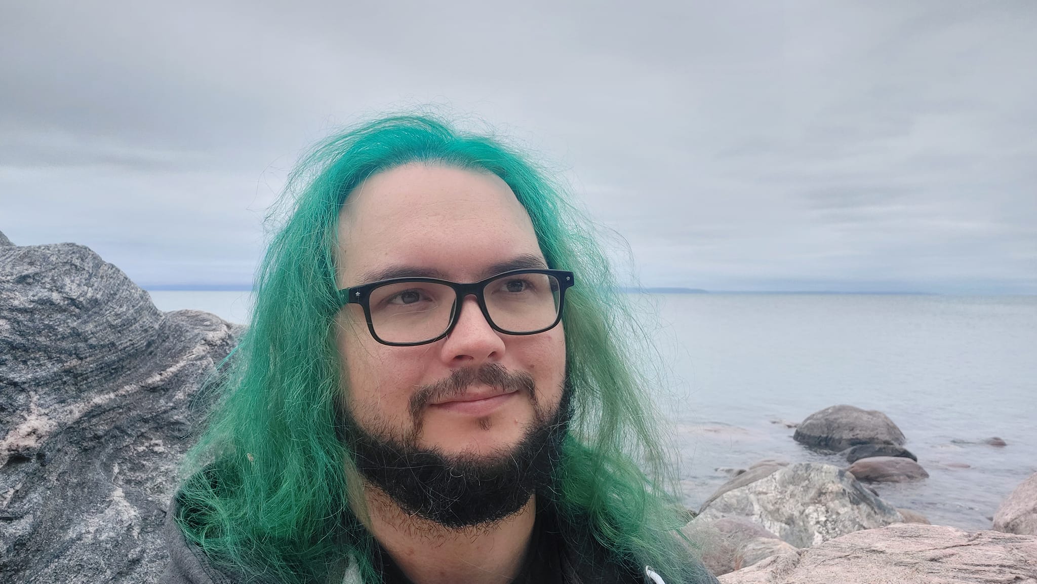 A man with green hair stands outside at a boulder breakwater, photo 14